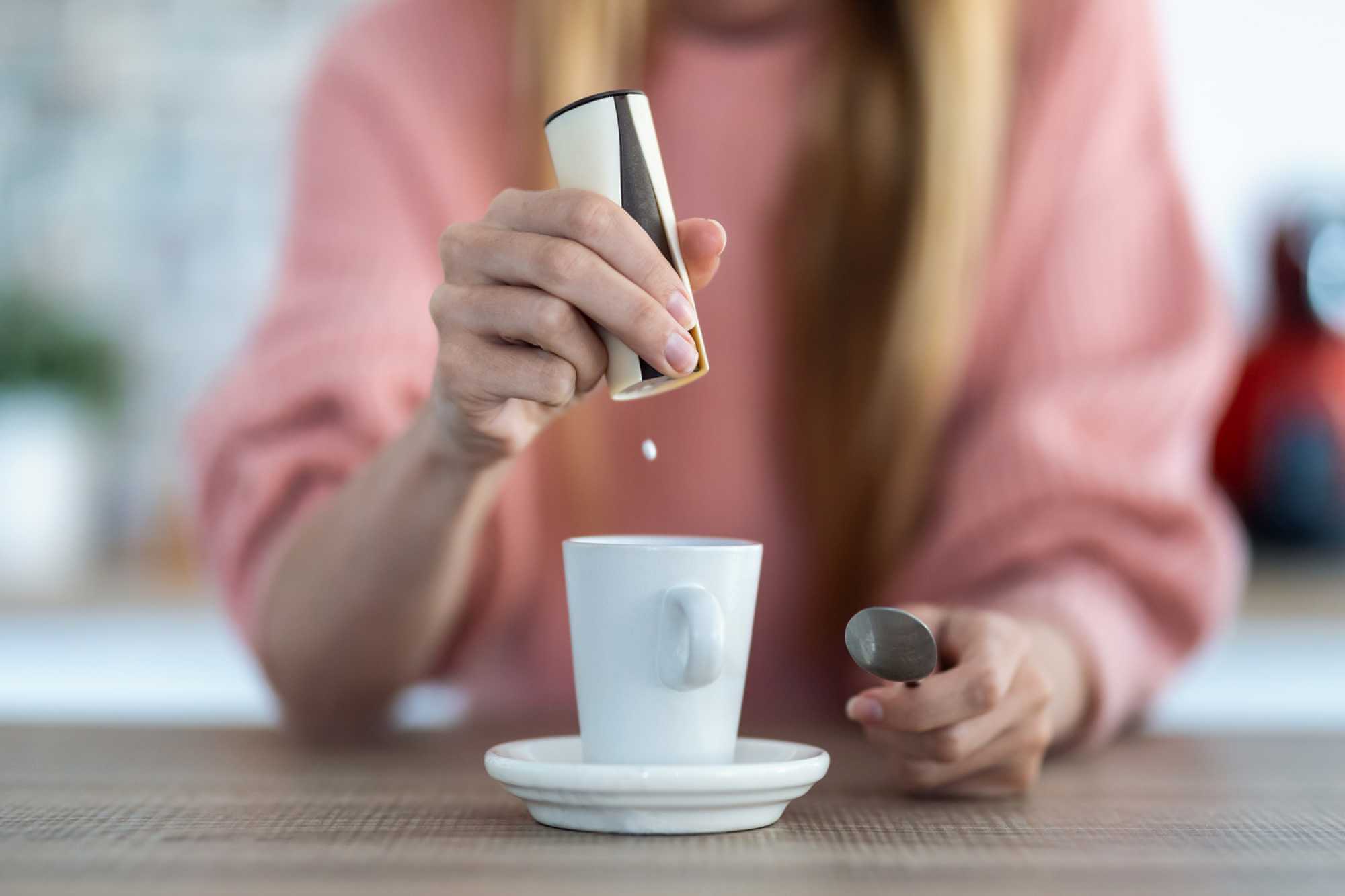 žena dává do kávy tabletu sladidla